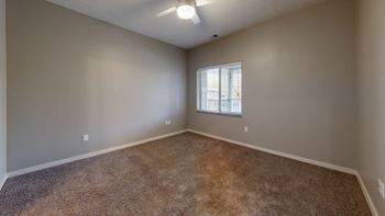 A room with a carpeted floor and a window with blinds.